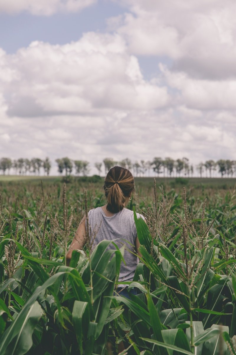 vrou in grys hemp wat bedags op groen grasveld staan